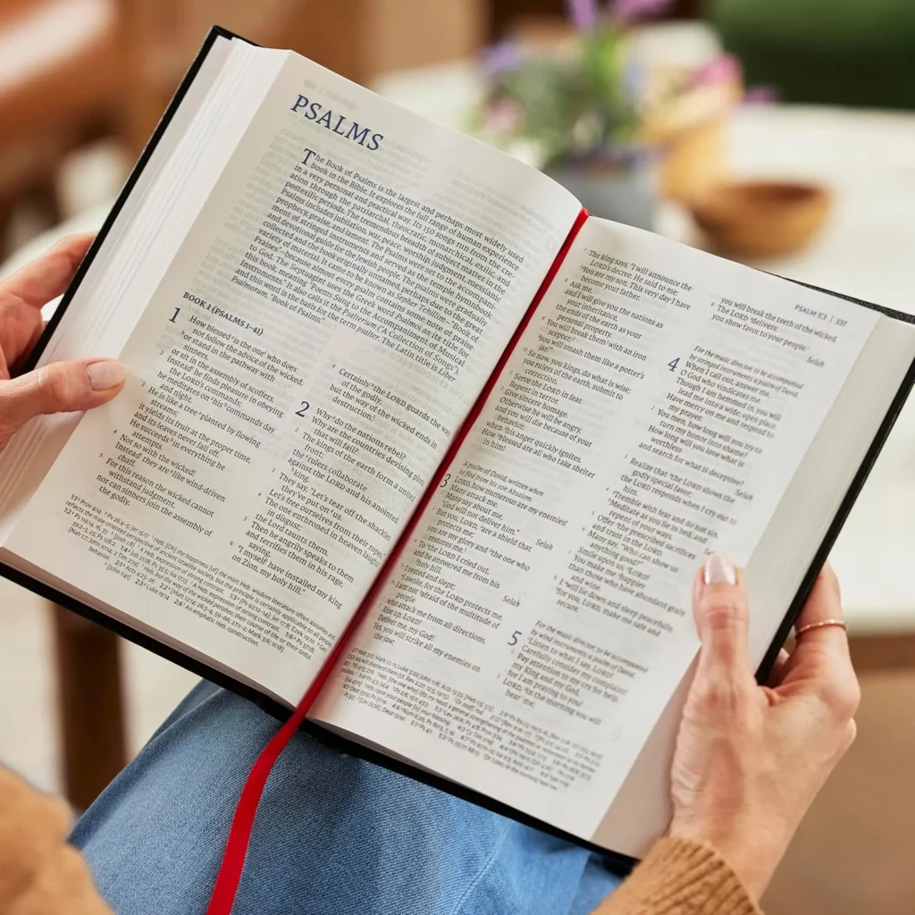 NET Thinline Reference Bible open on a table, a persons hands holding the pages open to Psalms
