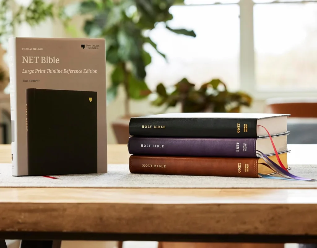 NET Large Print Thinline Reference Bible review illustrated by a stack of NET Bibles on display in various bindings and colors on a table, showing available formats