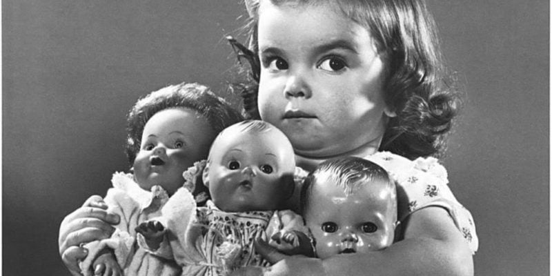 old photo of child holding dolls