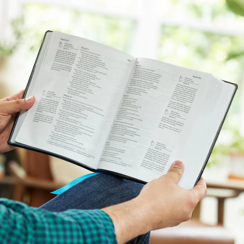 The Prayer Bible NIV by Thomas Nelson hardcover held open to Psalms showing the page layout, wide margins, and prayer prompts