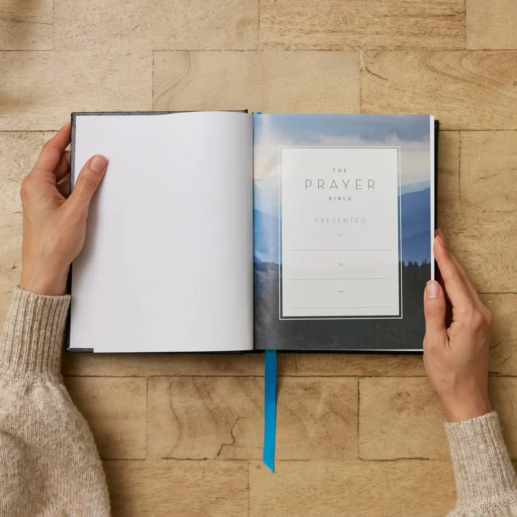 The NIV Prayer Bible hardcover on a wooden table, open to the presentation page