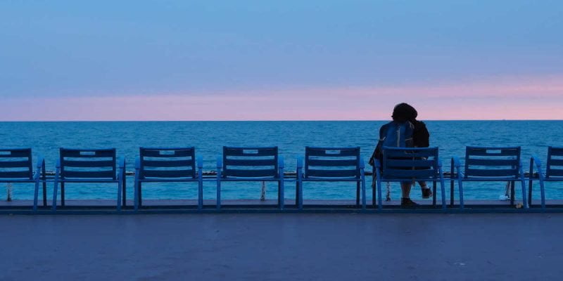 woman sitting alone looking over the sea with a dark blue sky