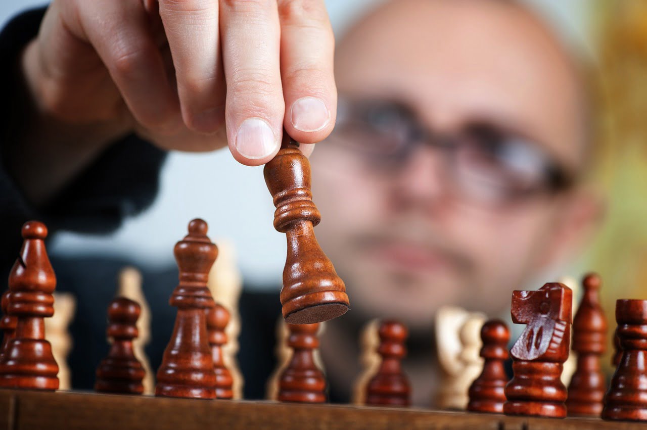 chess player moving a wooden chess piece
